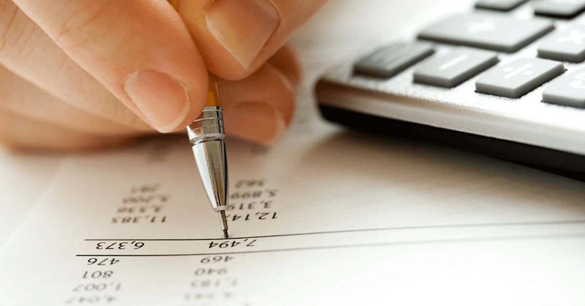 imagem de pessoa fazendo cálculos com uma caneta ao lado de uma calculadora, representando precificação de uma marca