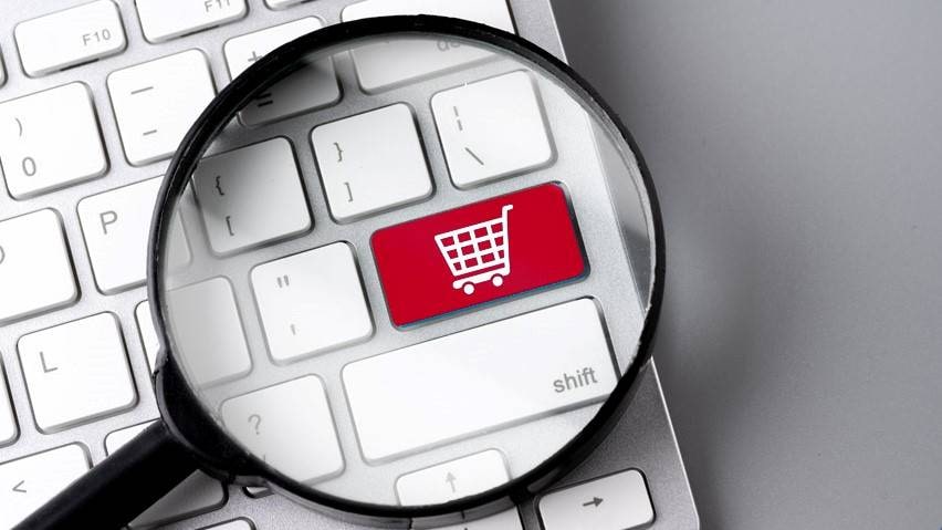 Imagem de uma tecla de computador vermelha com o desenho de um carrinho de supermercado branco, com uma lupa ampliando a imagem