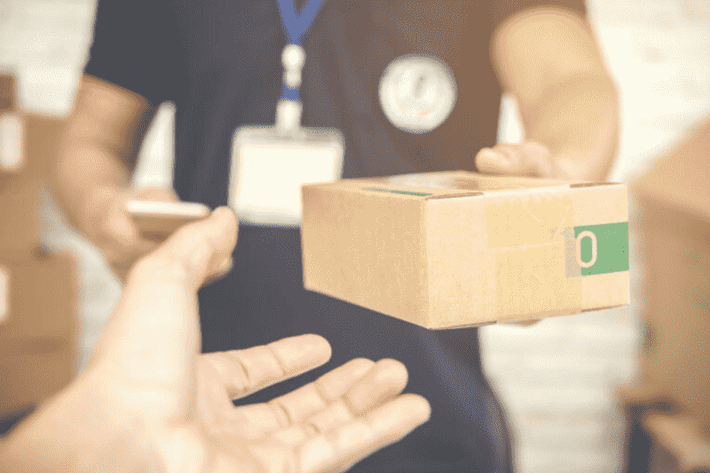 Imagem de uma pessoa entregando um produto em uma caixa