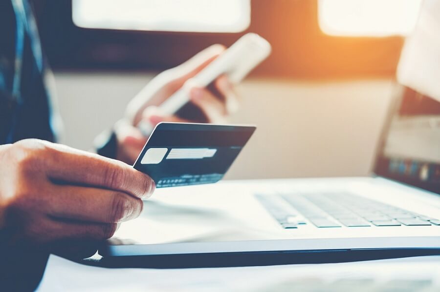 Imagem de uma pessoa segurando um cartão de crédito para usar em uma compra online
