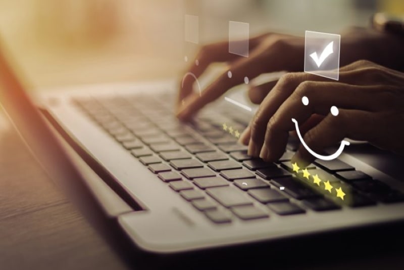 Imagem de uma pessoa usando um computador e, sobre sua mão, o desenho de 5 estrelas e um sorriso.