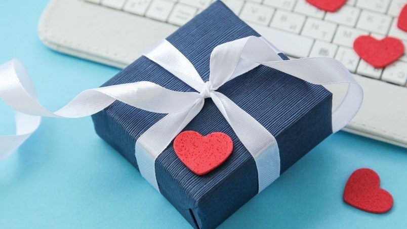 Caixinha de presente azul com um laço branco e corações espalhados ao redor