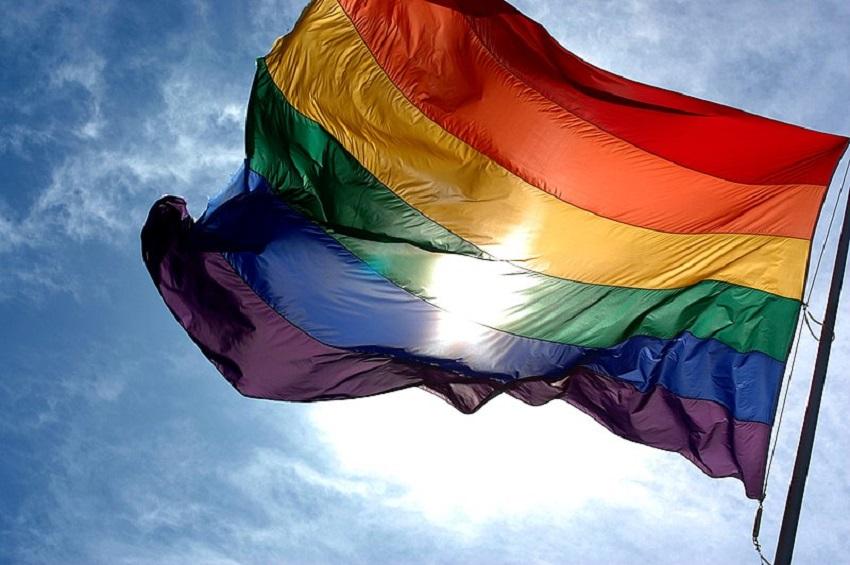 Imagem de uma bandeira com as cores do arco-íris representando pessoas LGBTQIA+