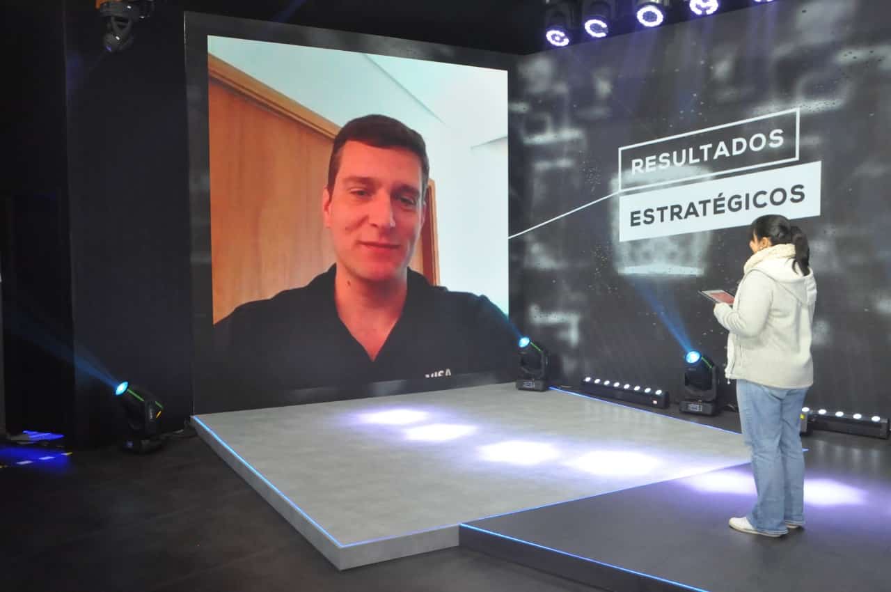 Imagem de palestrante em monitor sobre palco do evento