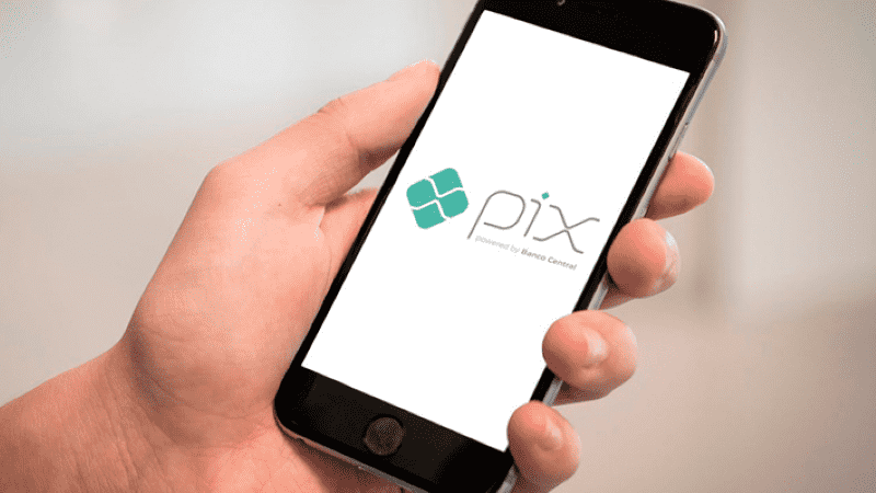 Imagem de uma pessoa segurando smartphone com o aplicativo do Pix na tela
