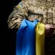 Imagem do busto de um soldado fardado segurando uma bandeira da Ucrânia