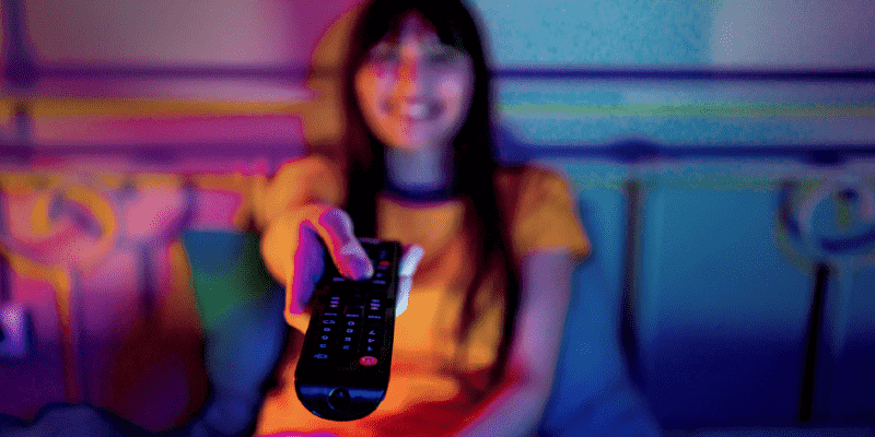 Imagem de uma garota sorrindo com um controle remoto na mão