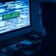 Homem de capuz utilizando computador para ataque cibercriminoso
