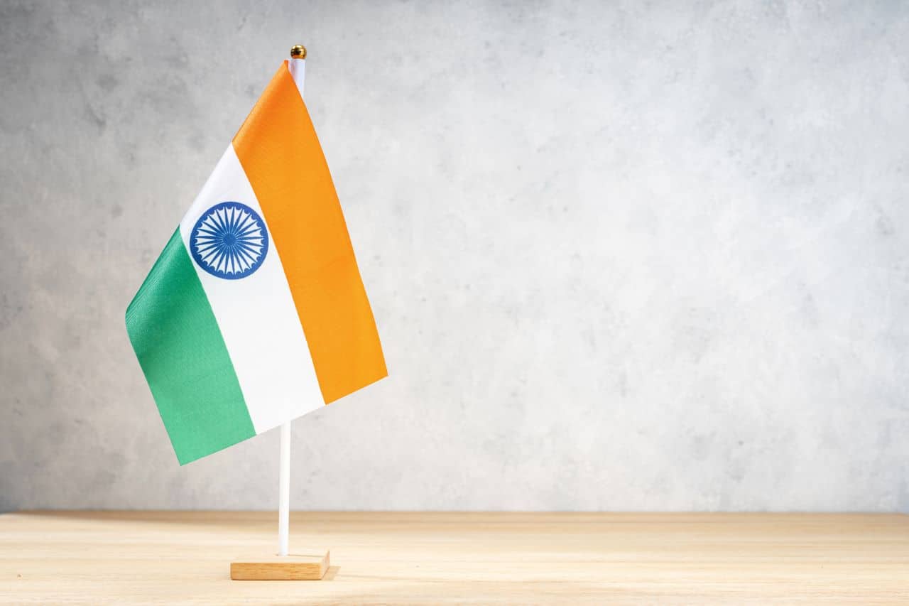 Imagem da miniatura de uma bandeira da Índia hasteada em um mastro sobre uma mesa