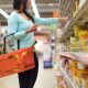 Imagem de uma mulher no supermercado segurando uma cesta com alimentos