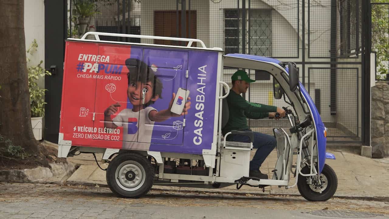 Imagem de um veículo do tipo tuk tuk personalizado da Casas Bahia com um motorista dentro