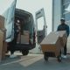 Imagem de um profissional de logística carregando caixas manualmente por meio de um carrinho de carregamento